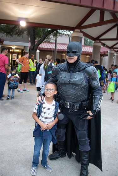 Batman standing with his hand on the should of a child.
