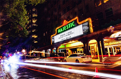 Majestic Theater at night with car lights captured in streaking lines.