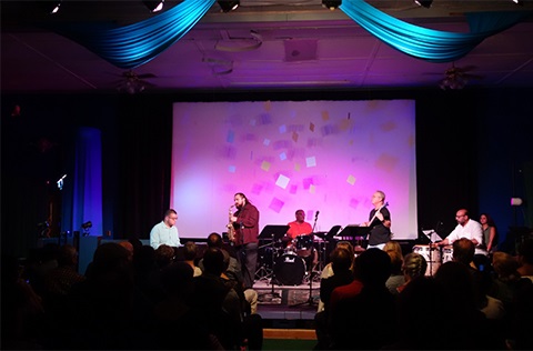 A group of people performing at a music event, playing instruments and creating music together.