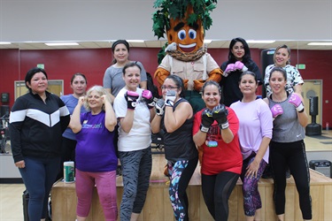 A group of women smiling and posing for a photo with a mascot at an event.