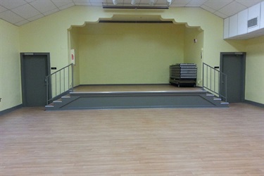 A spacious room with a stage and stairs, offering ample space for performances.