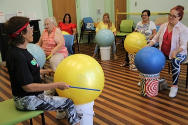 A group of women joyfully playing with oversized balls in a spacious room.