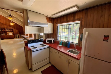 A kitchen with a stove, refrigerator, and sink.