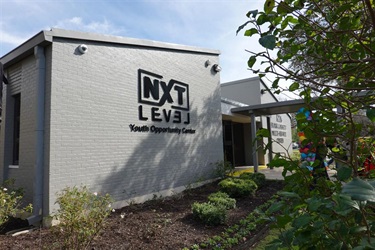 A grey building with the next level youth opportunity center sign on the outside wall.