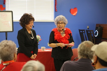 Two women on headsets presenting to a room full of people