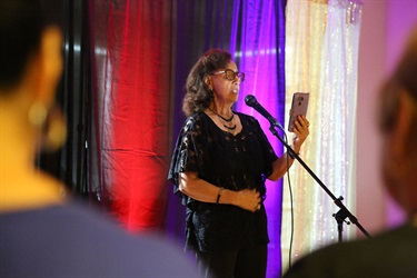 A woman reading from a cellphone into a microphone