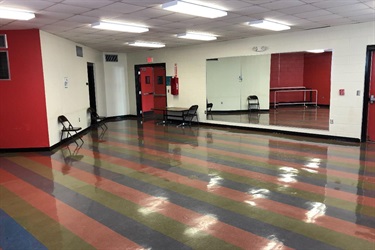 A dance studio with mirrored walls and a striped floor