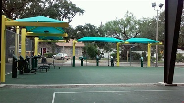 Outdoor fitness stations covered by green pavilions.