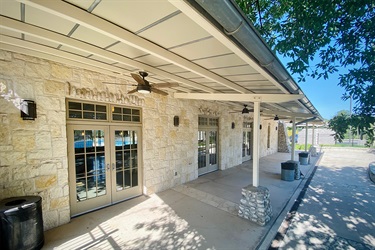 Entrance to building with stone wall and outdoor ceiling fans.