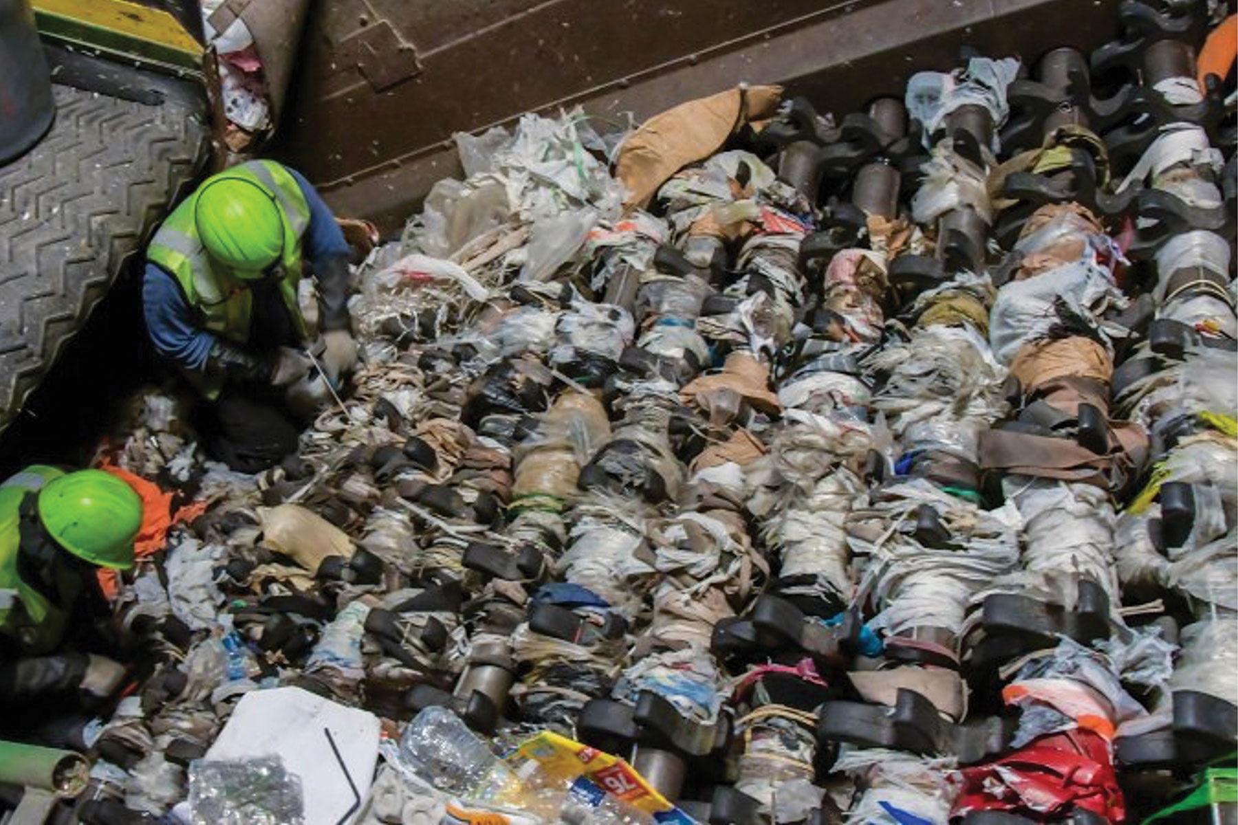 A worker sorts through a large pile of plastic bags for recycling or waste management purposes.